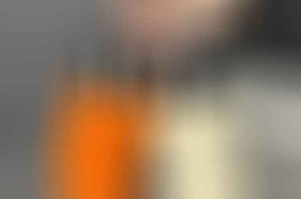 A hand is holding two Mini Couple Cup Tumblers with metal caps, one in orange and the other in cream-colored, against a gray background with a quote in cursive above.