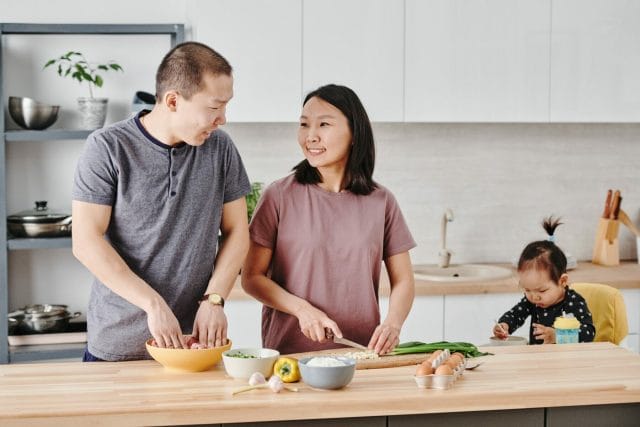 a couple doing their relationship ritual of cooking together with their child nearby, Uncover the Benefits of Relationship Rituals, couple things ph