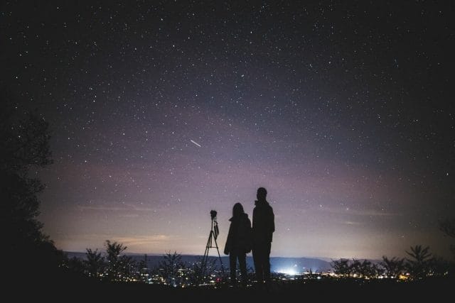 A couple looking at the stars with a telescope.