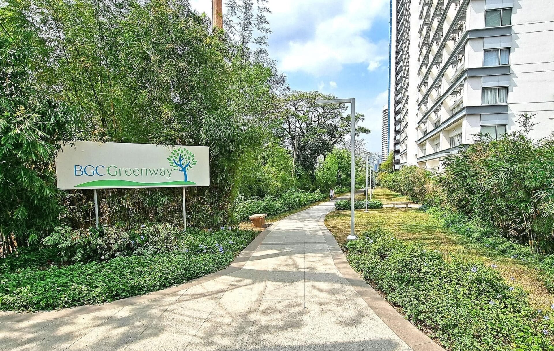pathway with trees and a sign board saying BGC Greenway Park