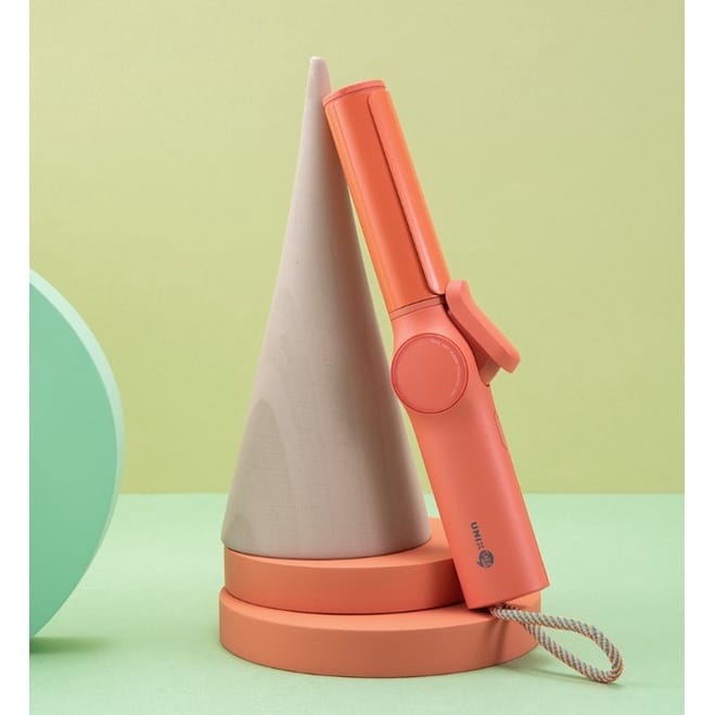 A pink UNIX Mini Wireless Iron Collection sitting on top of a cone.