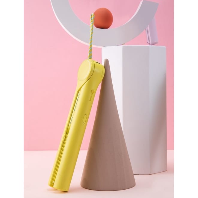A yellow and pink UNIX Mini Wireless Iron Collection sitting on top of a pink pedestal.